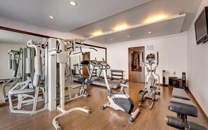 Un gimnasio con diferentes máquinas de ejercicio, una cinta de correr y una bicicleta estática.