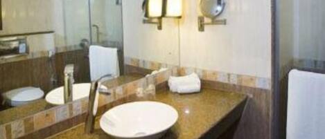 Un baño moderno con encimera de granito, dos lavamanos, un espejo grande y cabina de ducha de vidrio.