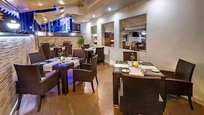 Un restaurante con mobiliario de mimbre, suelo de madera y ventanas amplias.