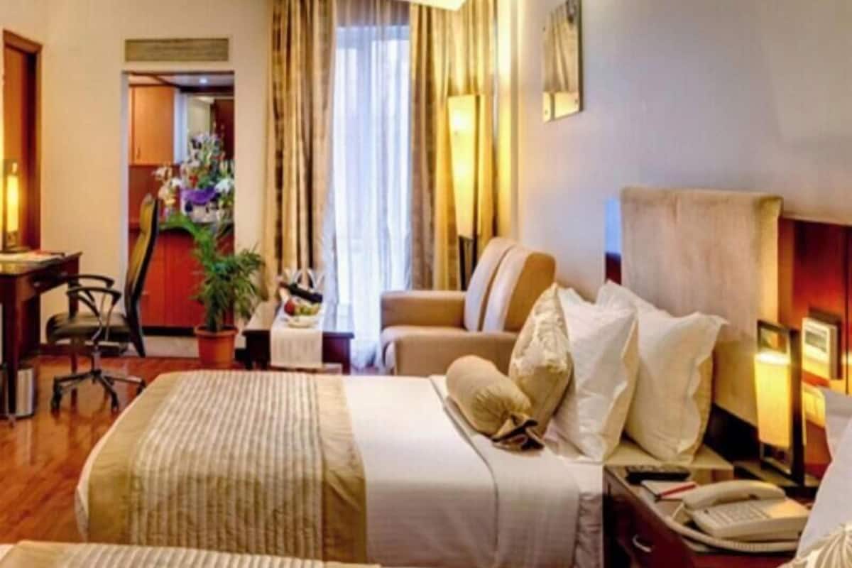 Ein Hotelzimmer mit Bett, Nachttisch, Lampe und Schreibtisch mit Stuhl.