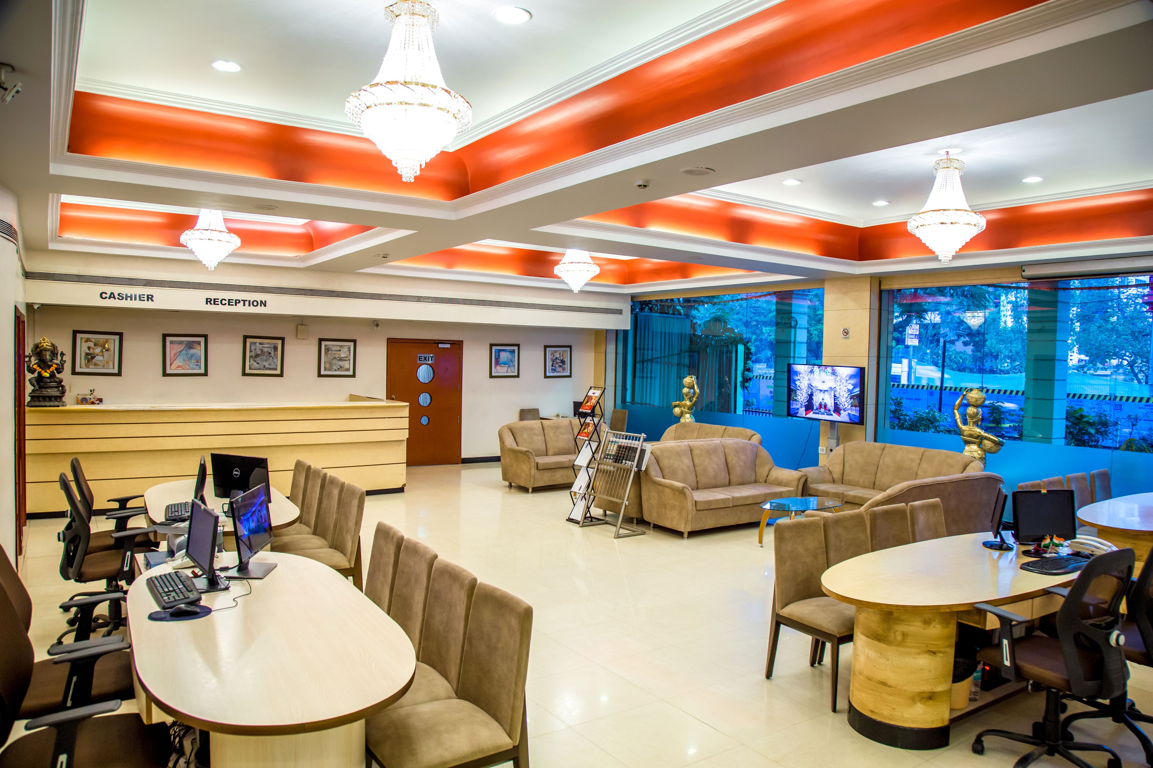 A hotel reception area with a cashiers desk, reception chairs, and a large window with a view of trees.