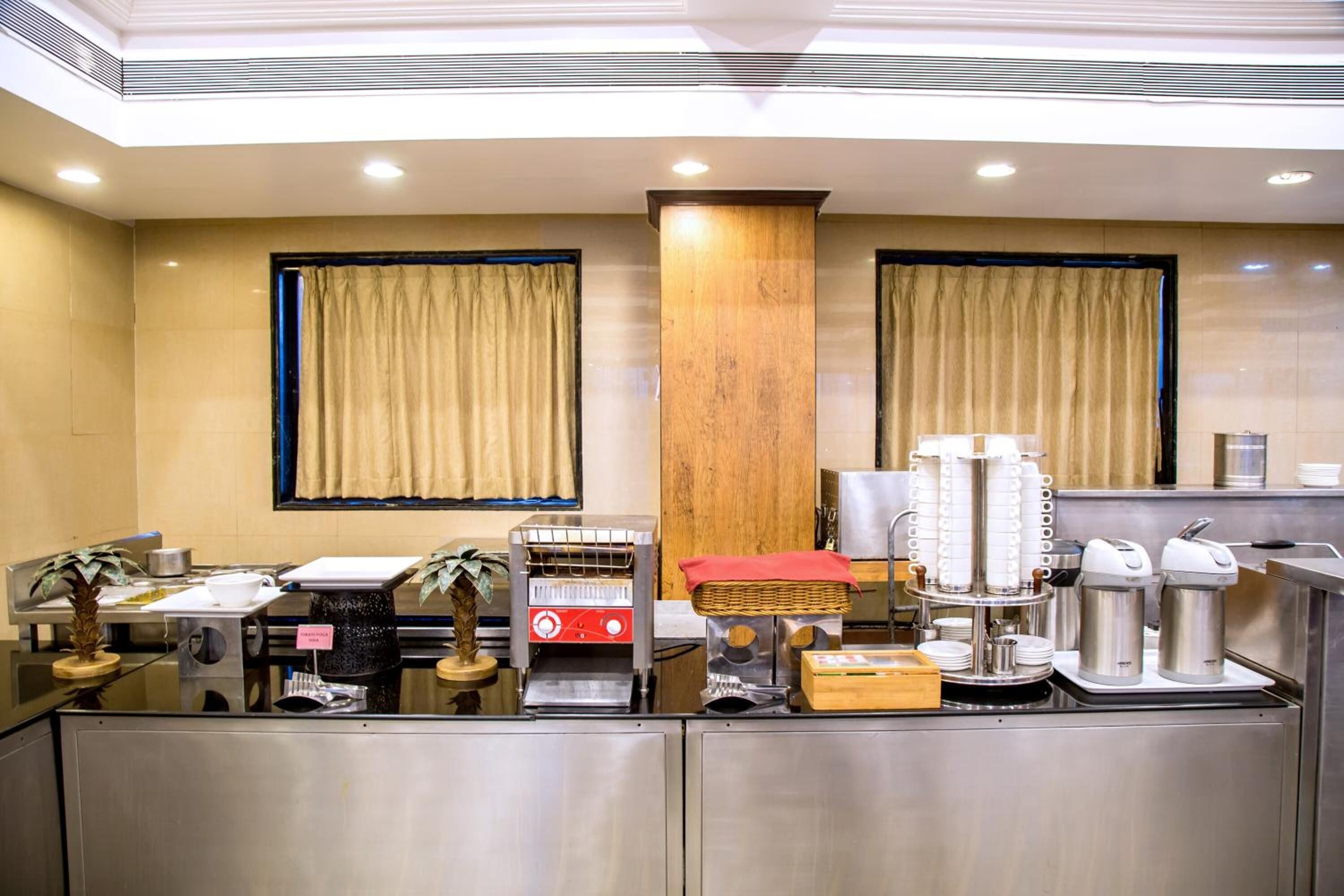 A hotel reception area with a counter, coffee machines, and a plant.