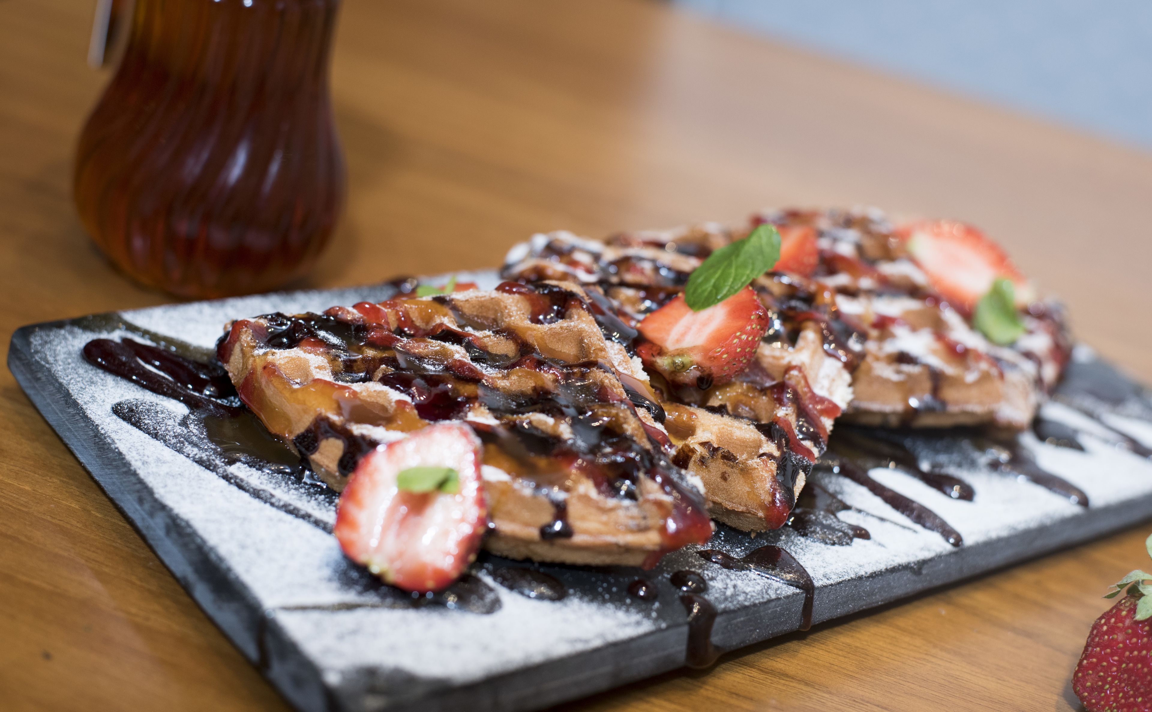 A plate of French toast with strawberries and chocolate sauce.