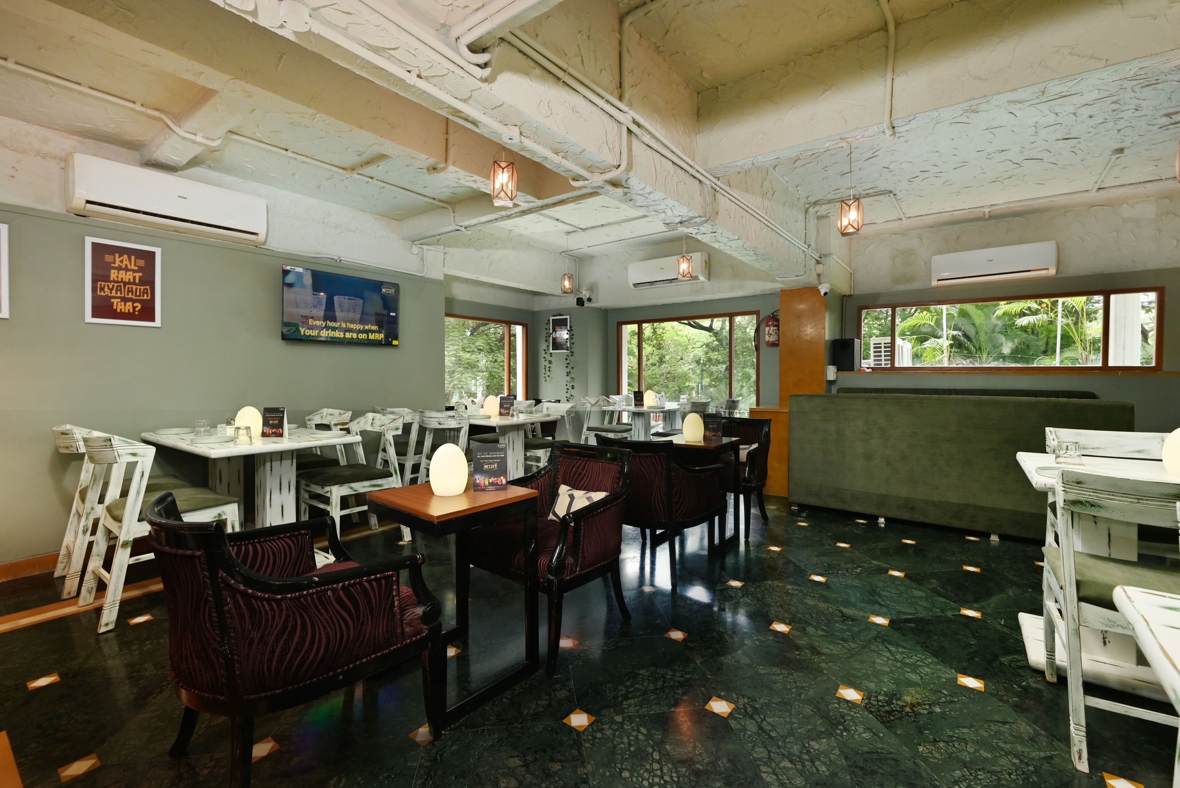 A restaurant with tables and chairs, air conditioning units, and a view of greenery outside.