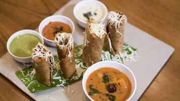 Un plato de samosas acompañadas de diferentes salsas para mojar y un tazón de sopa.