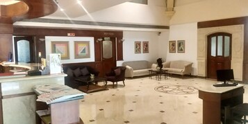 Un hall con mostrador de recepción, sofás, una mesa de centro y un suelo estampado.