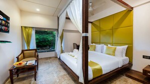 A four-poster bed with a canopy, a wooden chair with a cushion, a small table with a basket of fruit, and a window with curtains. - VITS Sharanam, Thane (Thane)