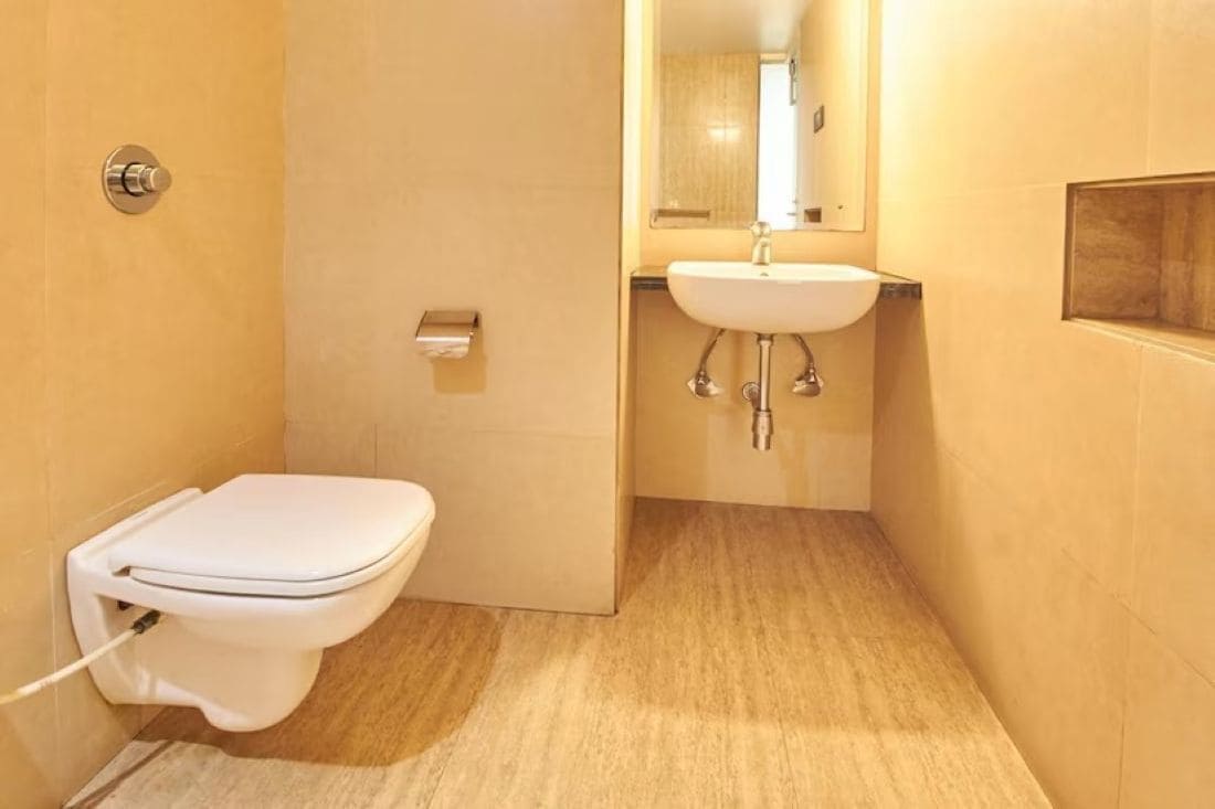 A small, compact bathroom with a toilet, sink, and mirror.