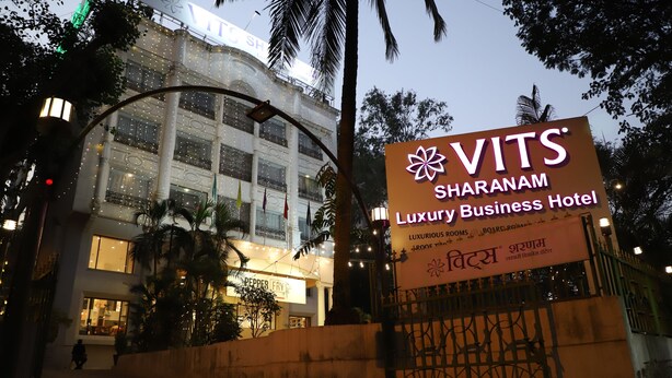 A sign for VITS Sharanam Luxury Business Hotel with a modern building in the background. - VITS Sharanam, Thane (Thane)