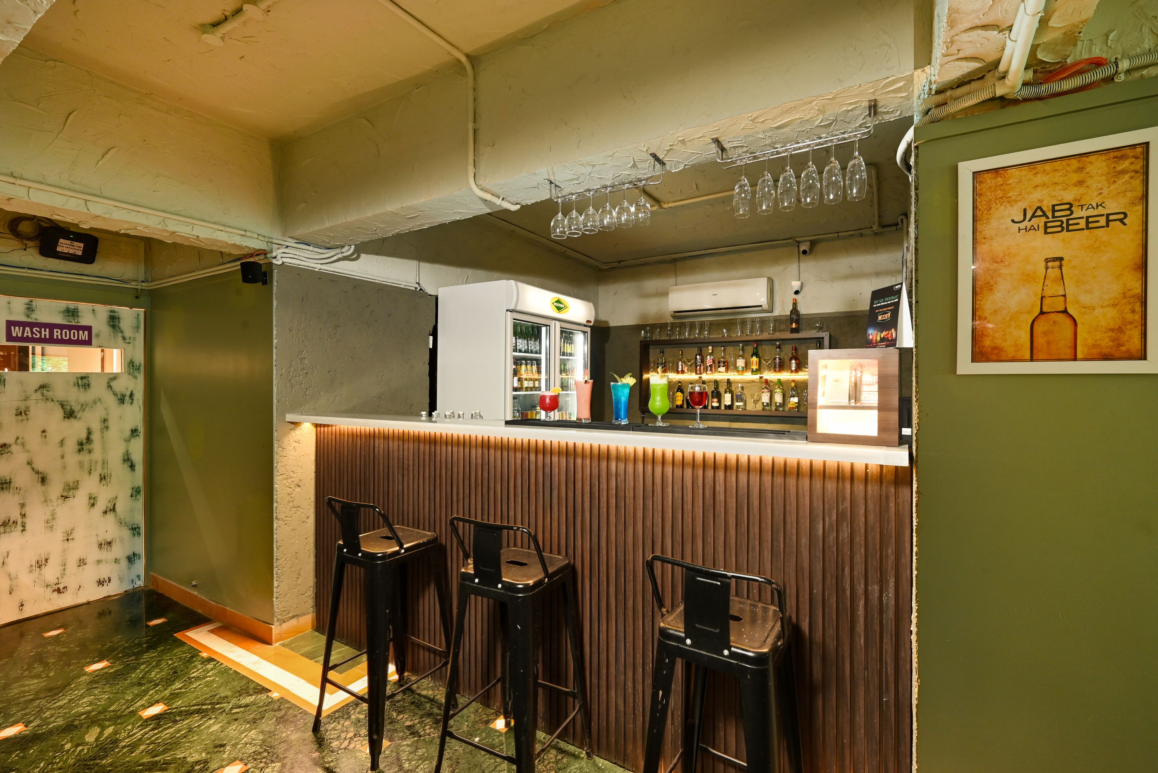 A bar area with stools, a refrigerator, and a wall-mounted wine rack.