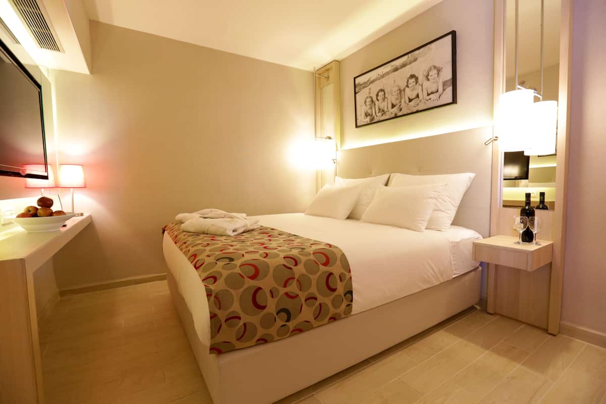 Une chambre d’hôtel avec un lit, une table de chevet, une lampe et un tableau encadré au mur.