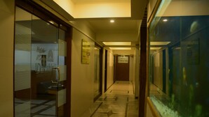 Un couloir d’hôtel avec des portes en verre, un espace de réception et un aquarium.