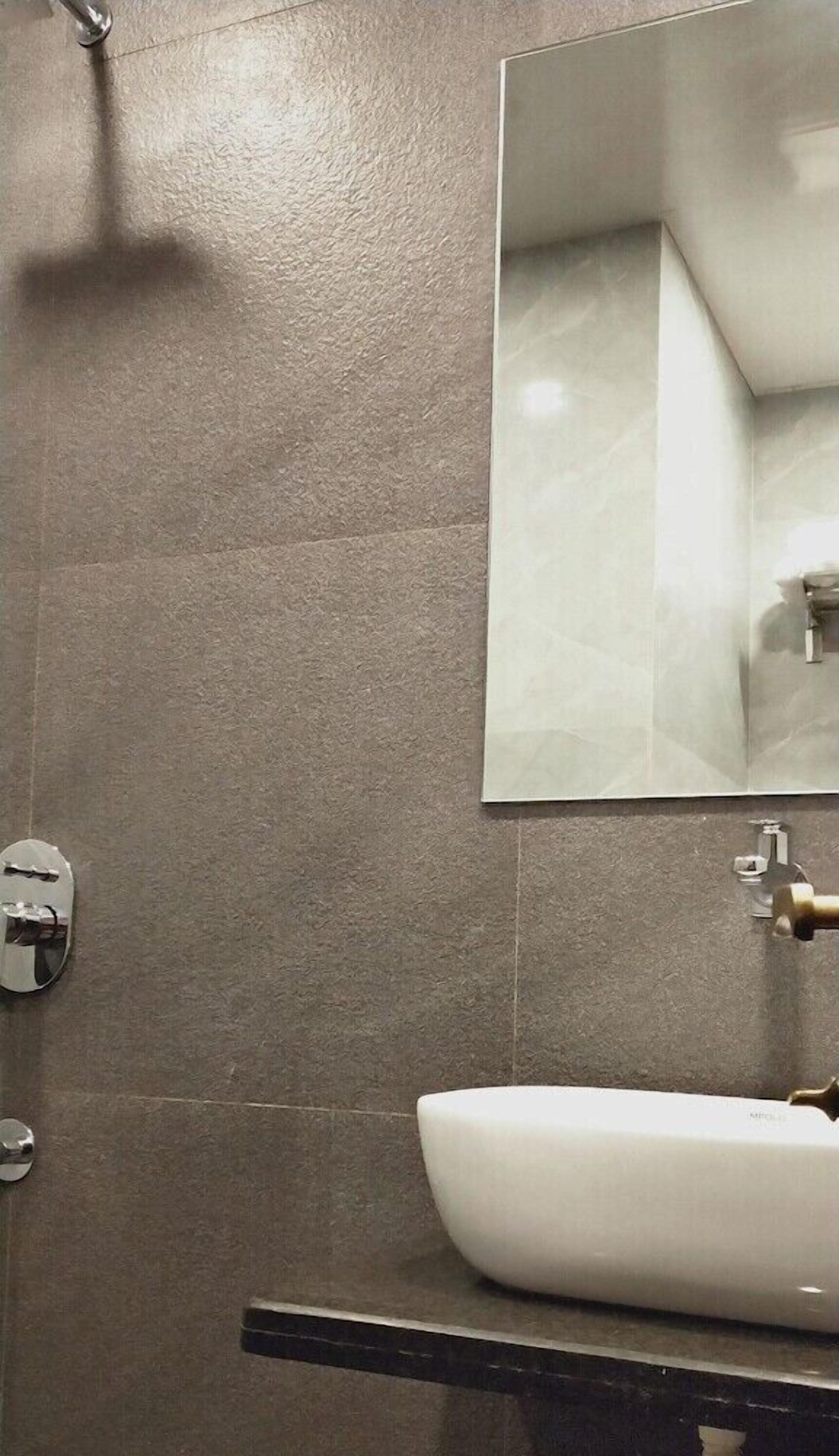 A bathroom with a white sink, a mirror, and a shower head.