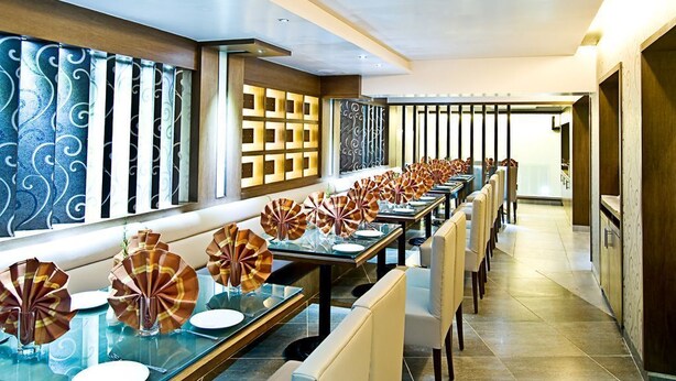 Une grande salle à manger avec des tables disposées pour accueillir de nombreux convives, agrémentée de décorations centrales et dotée d’un aménagement intérieur moderne.