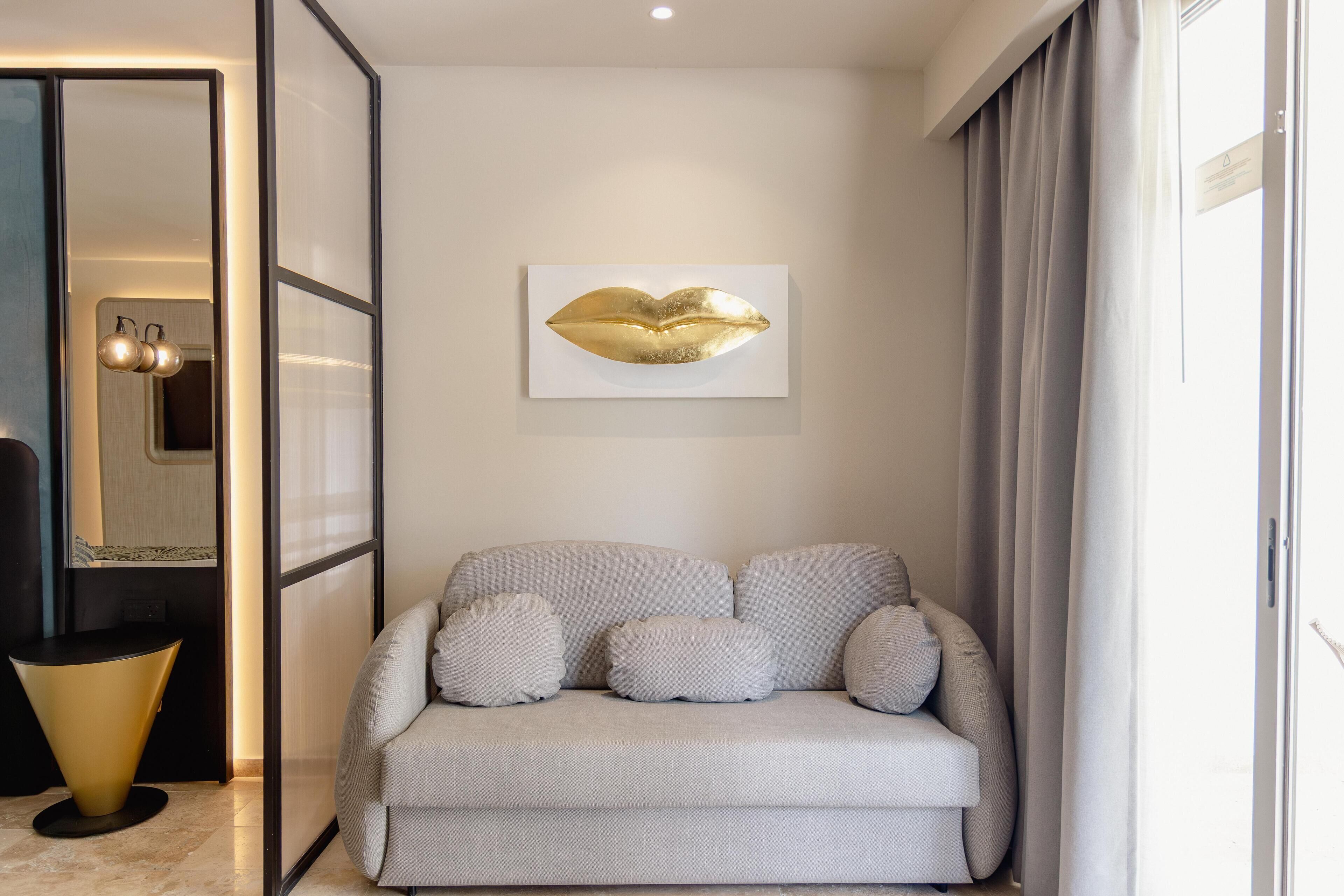 A modern living room with a grey sofa, a gold abstract artwork, and a round table.