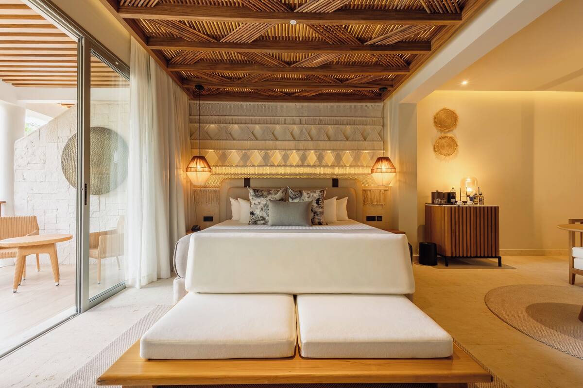 A modern bedroom with a large bed, a wooden ceiling, and a glass wall.