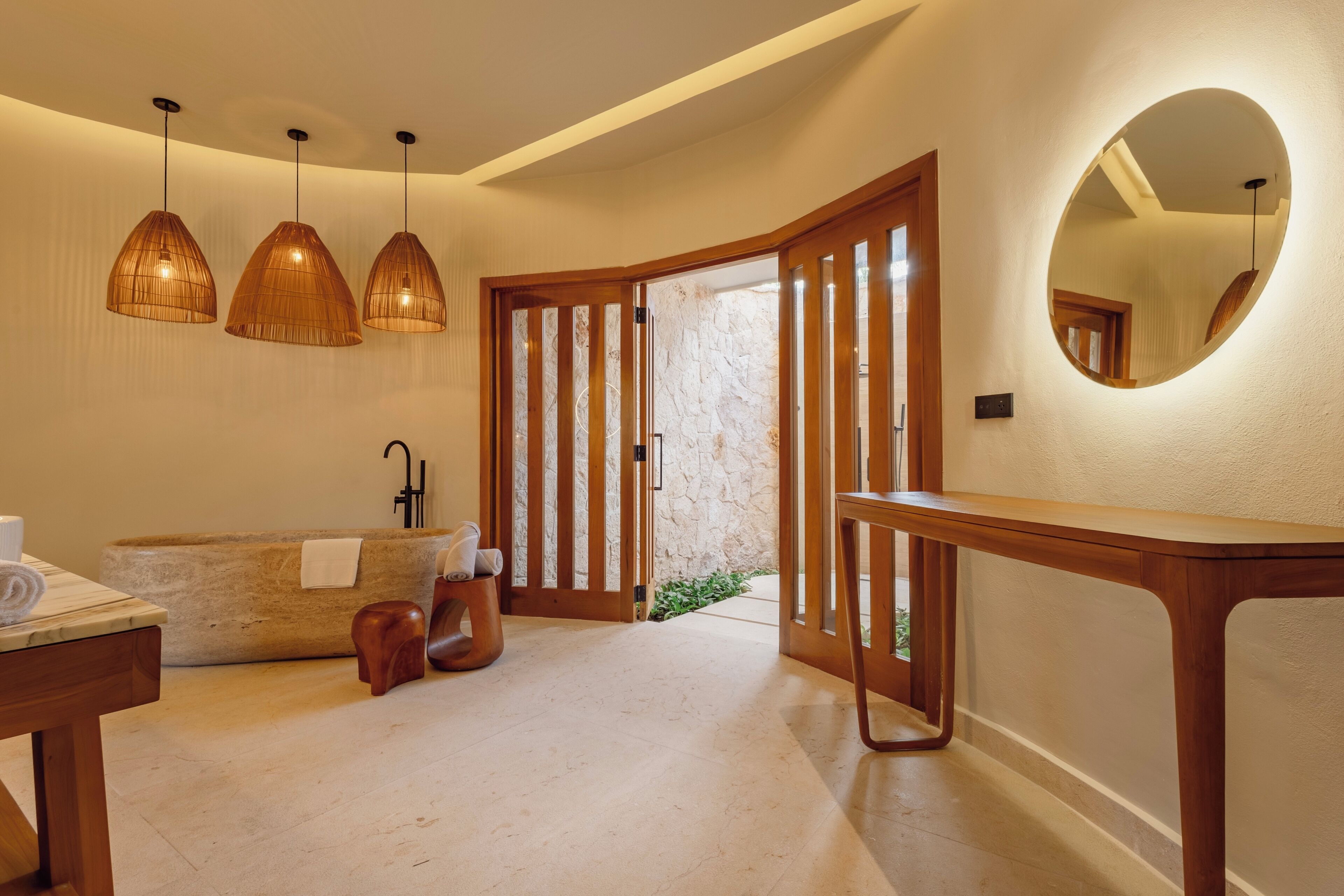 Un baño moderno con una bañera independiente, detalles de madera e iluminación colgante.