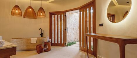 Une salle de bain moderne avec une baignoire sur pieds, des éléments décoratifs en bois et des luminaires suspendus.
