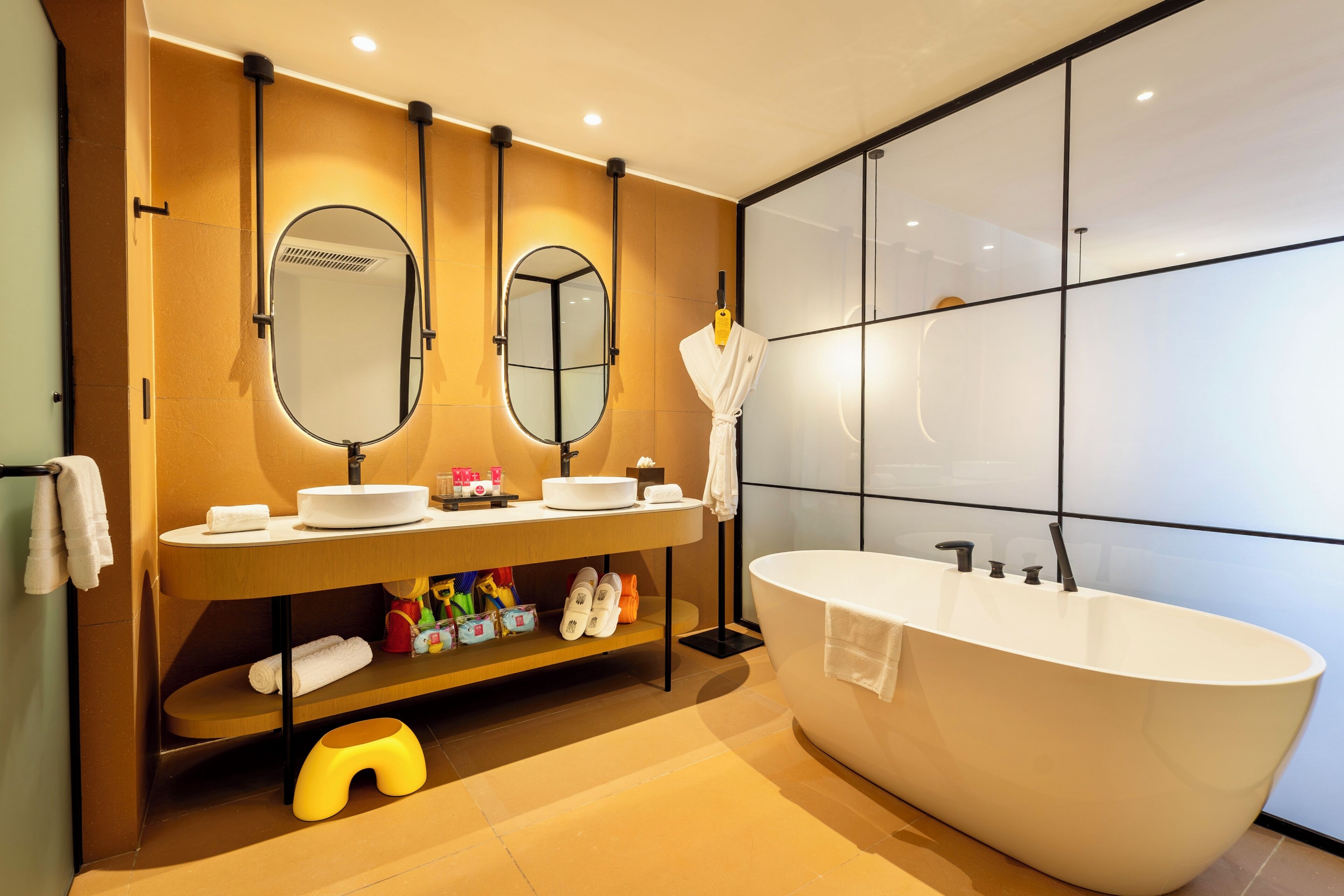 Een moderne badkamer met een vrijstaand bad, dubbele wastafels en een grote spiegel.