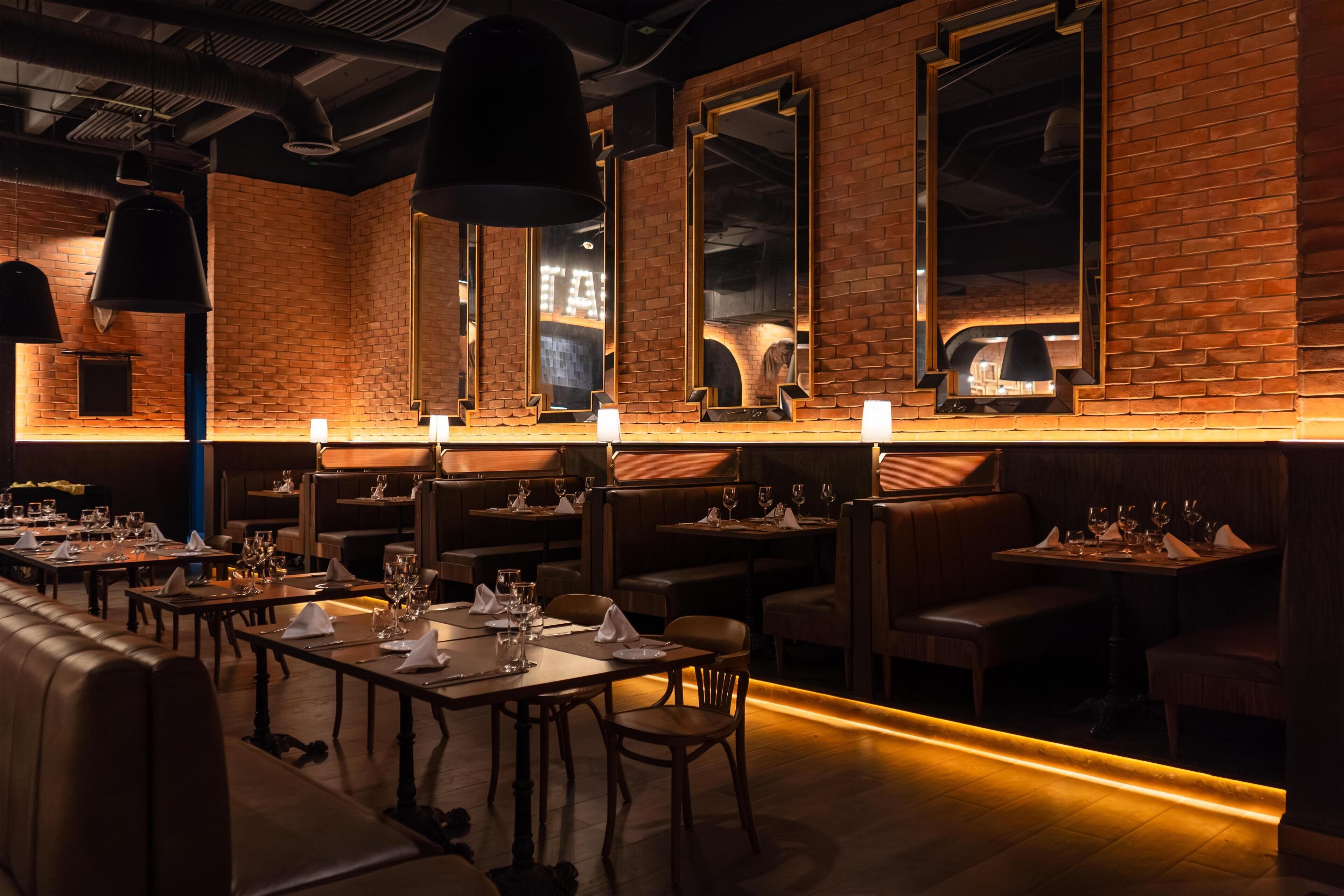 A restaurant with brick walls, wooden tables, and booths.