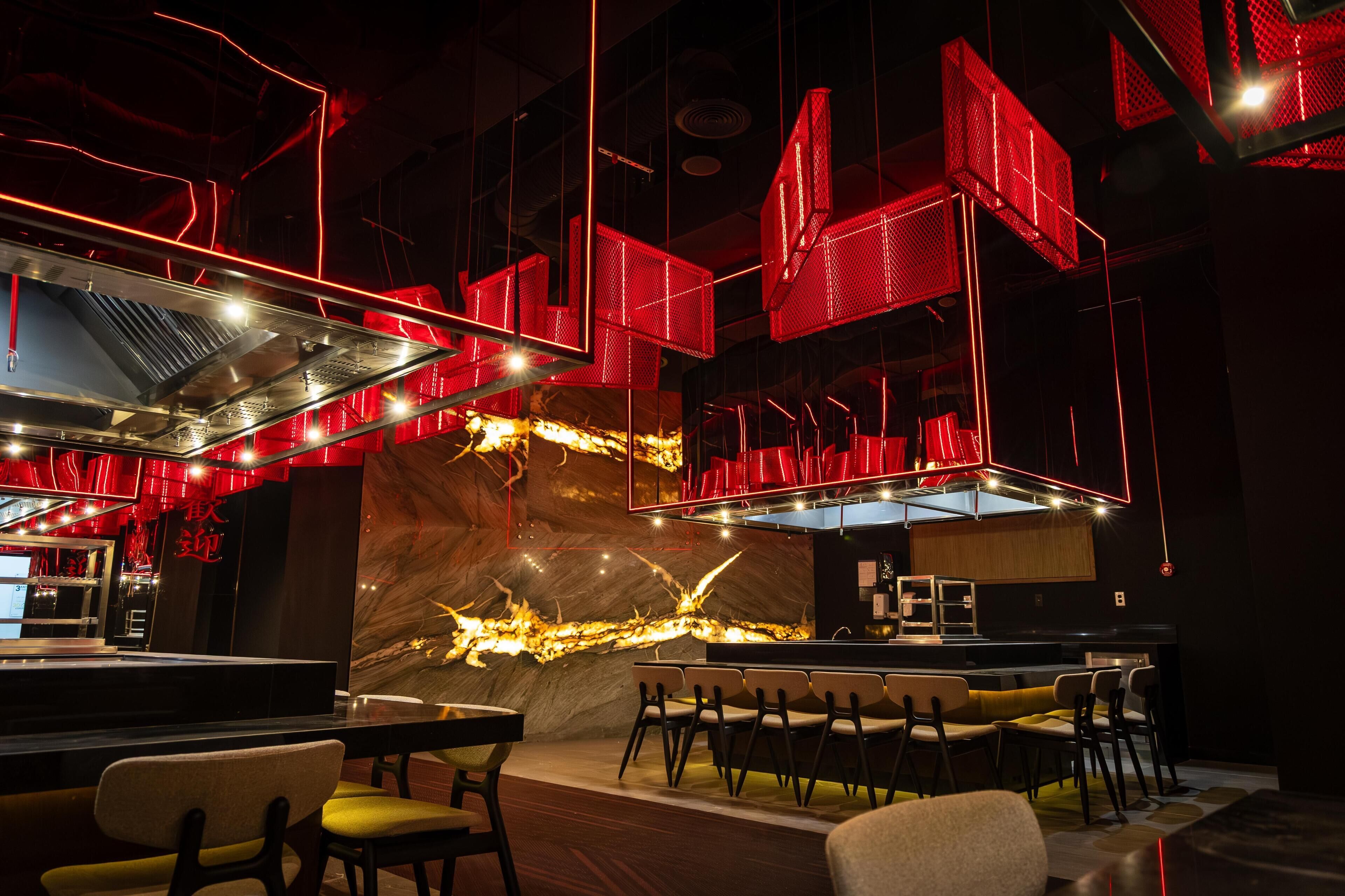 A modern bar area with red seating and a marble accent wall.