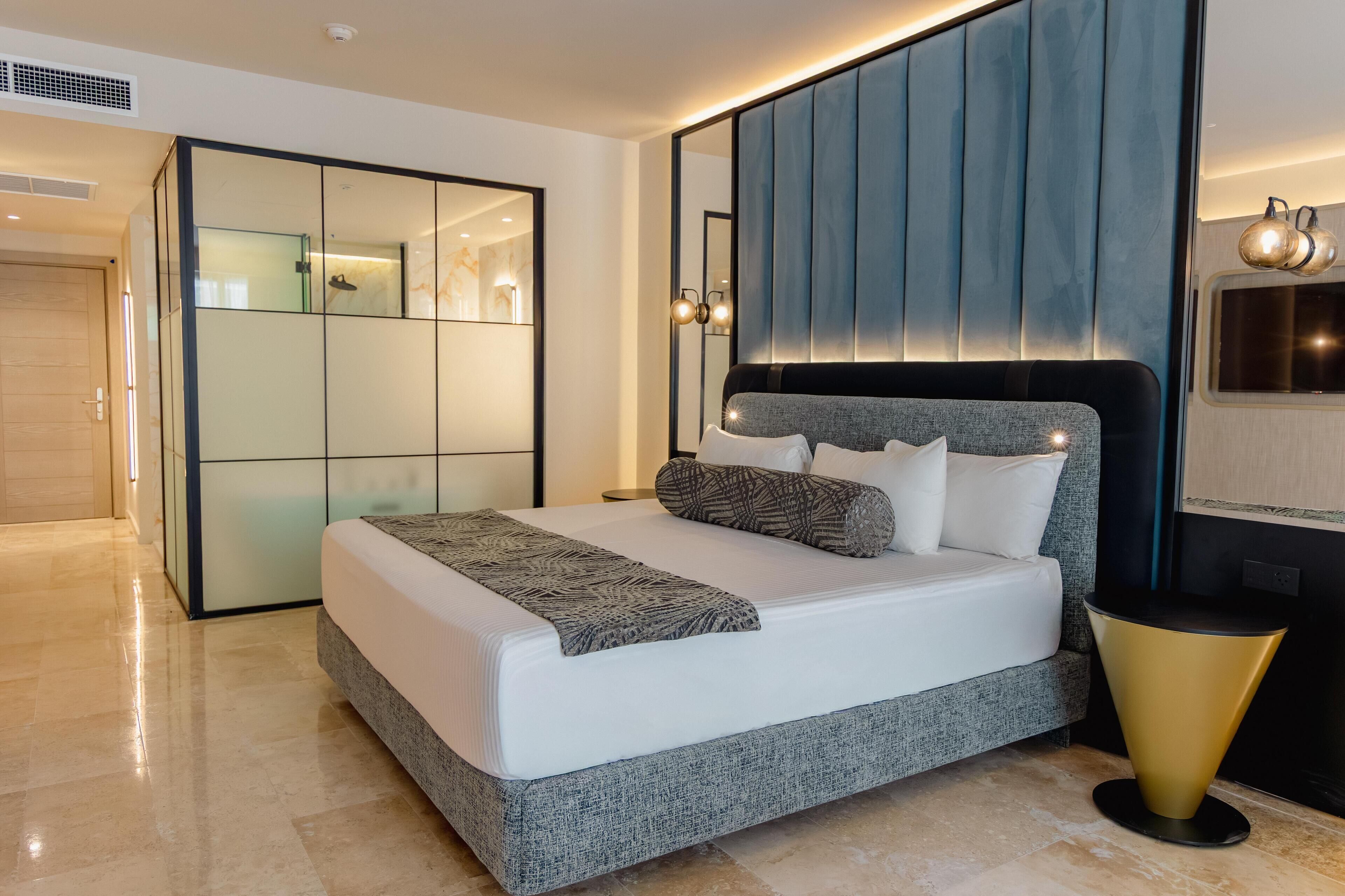 A modern bedroom with a large bed, a built-in wardrobe, and a bedside table.