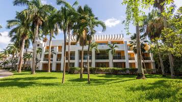 A hotel with multiple floors, palm trees, and a well-maintained lawn.
