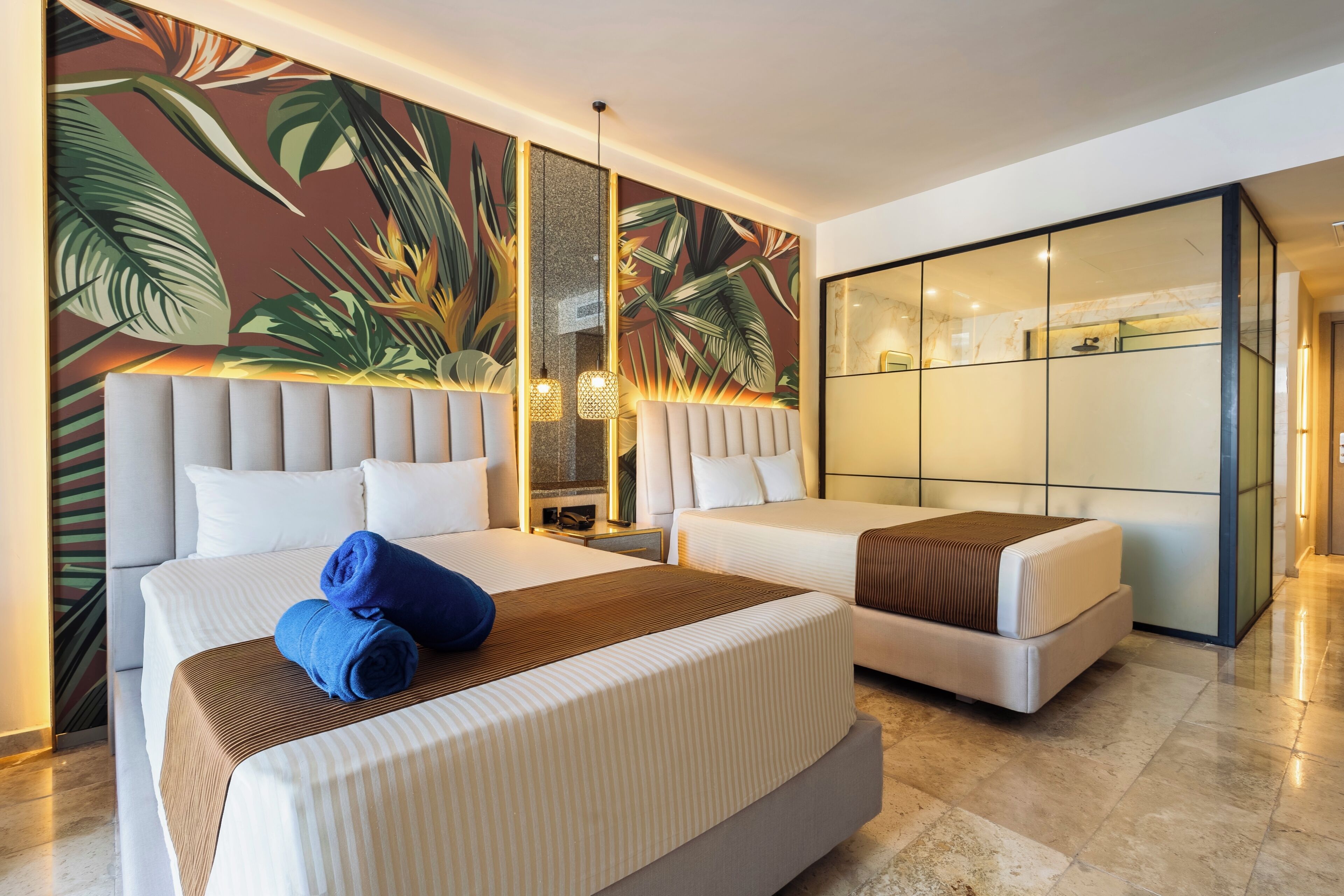 Camera d'albergo con due letti, un grande murale a tema tropicale e un design moderno.