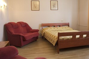 Un dormitorio con una cama de madera, un sofá rojo y dos cuadros en la pared.