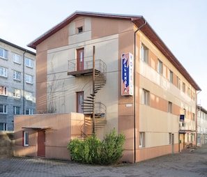Un hotel con una escalera de caracol, un letrero que dice "Hotel Lillekula" y un edificio de ladrillo contiguo.