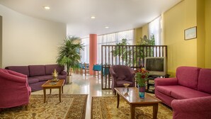 Uma sala de estar com dois sofás, uma mesa de centro, uma televisão e um espaço de jantar com mesa e cadeiras.