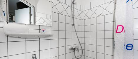 A bathroom with a white sink, mirror, and shower.