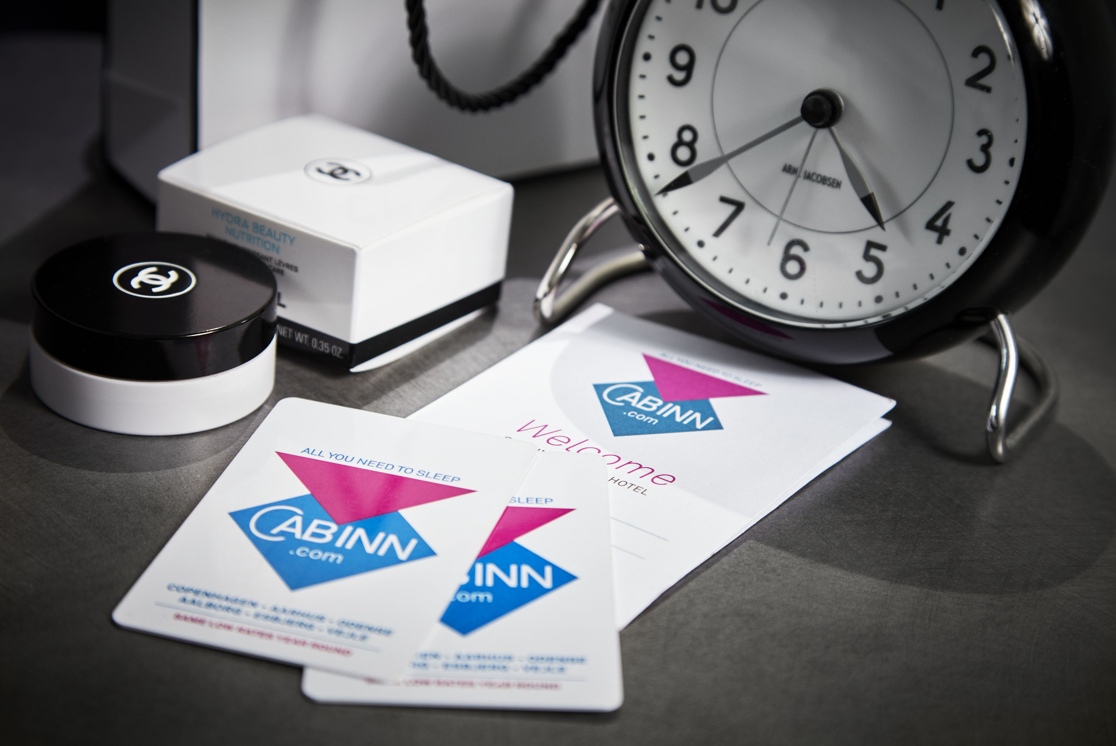 Un reloj, una caja y dos tarjetas de presentación sobre una mesa.