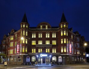 Ein historisches Hotel mit einem markanten Eingang, zahlreichen Fenstern und einem charakteristischen Eckturm.