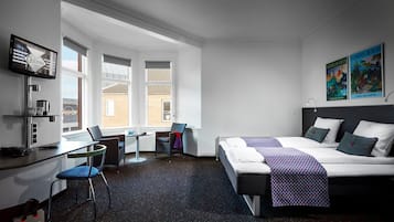 Habitación de hotel con cama, escritorio, silla y una pequeña mesa.