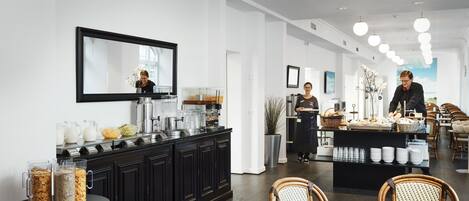 A modern dining area with a buffet setup, a large mirror, and a seating area with wicker chairs.