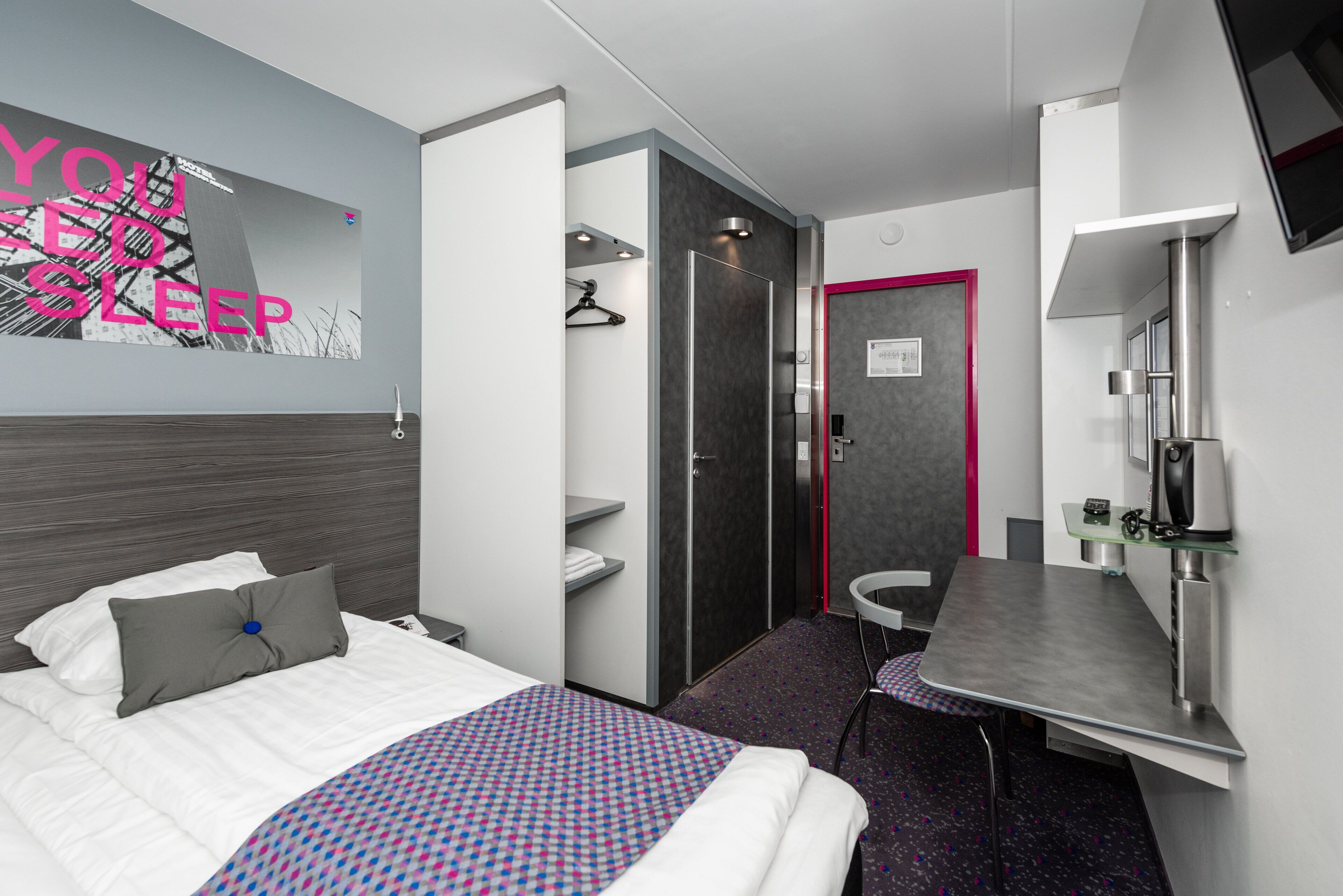 Una habitación de hotel moderna con cama, escritorio, ducha y televisión.