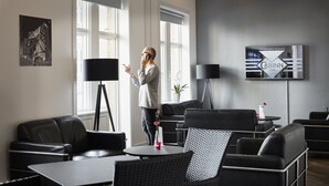 A modern hotel room with a large window, a flat-screen TV, a black lamp, and a potted plant. - CABINN Esbjerg Hotel (Esbjerg)
