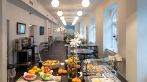 A buffet setup with various food items and a decorative vase with flowers. - CABINN Esbjerg Hotel (Esbjerg)