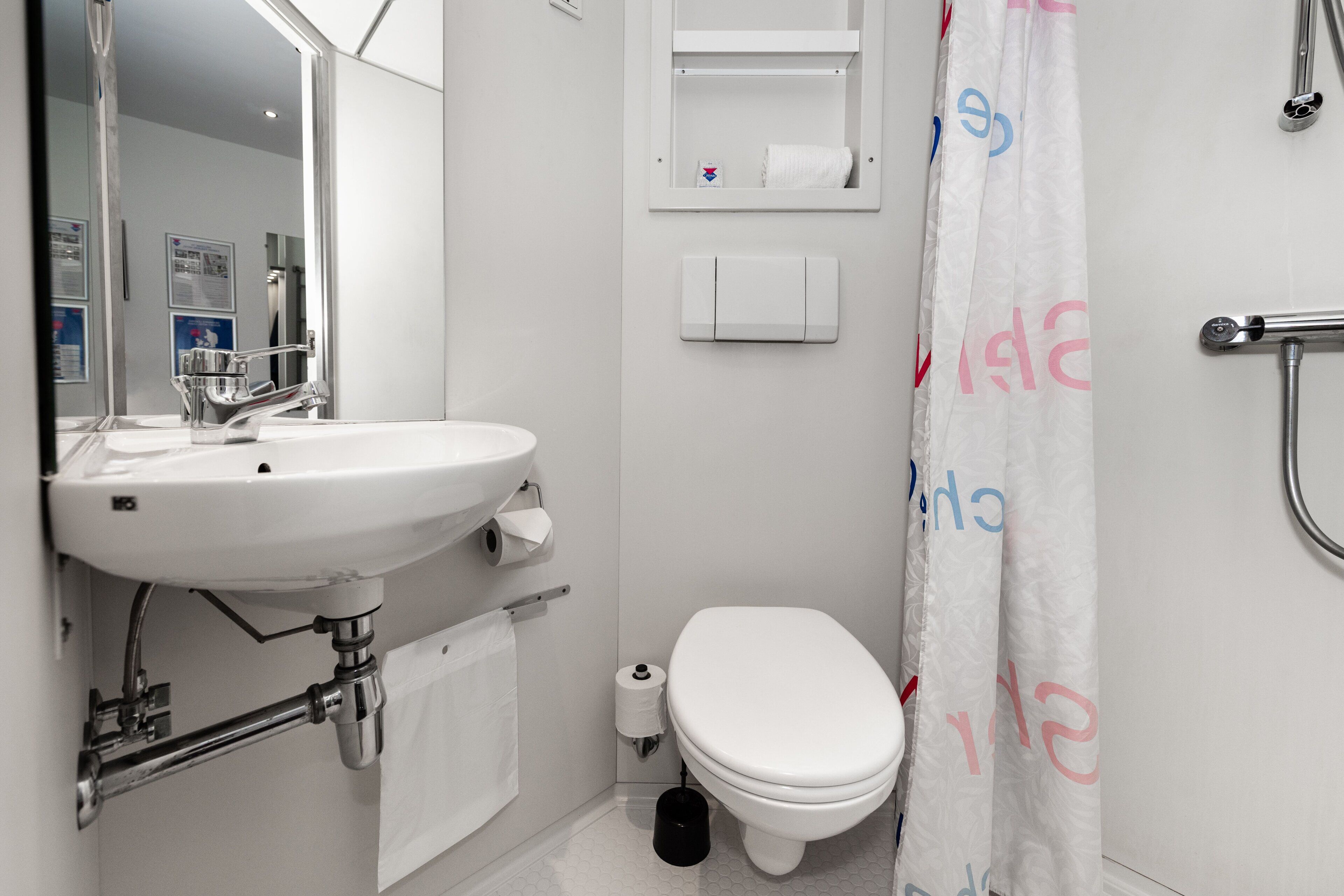 Et badeværelse med vask, toilet og badeforhæng.