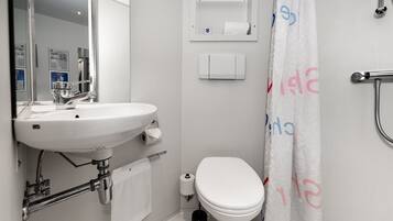 Et badeværelse med vask, toilet og badeforhæng.