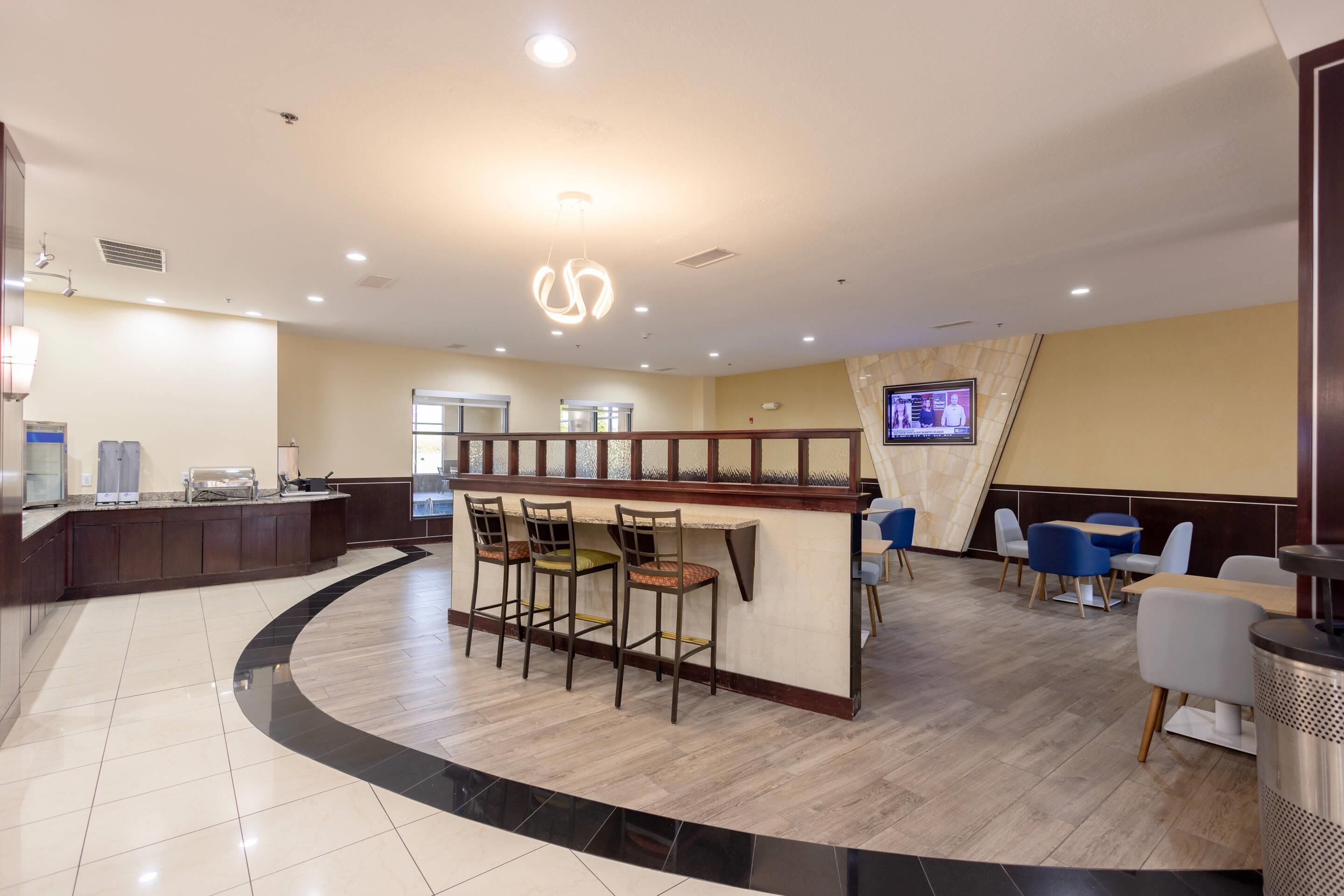 Um hall de hotel moderno com balcão de recepção curvo, área de bar e assentos.