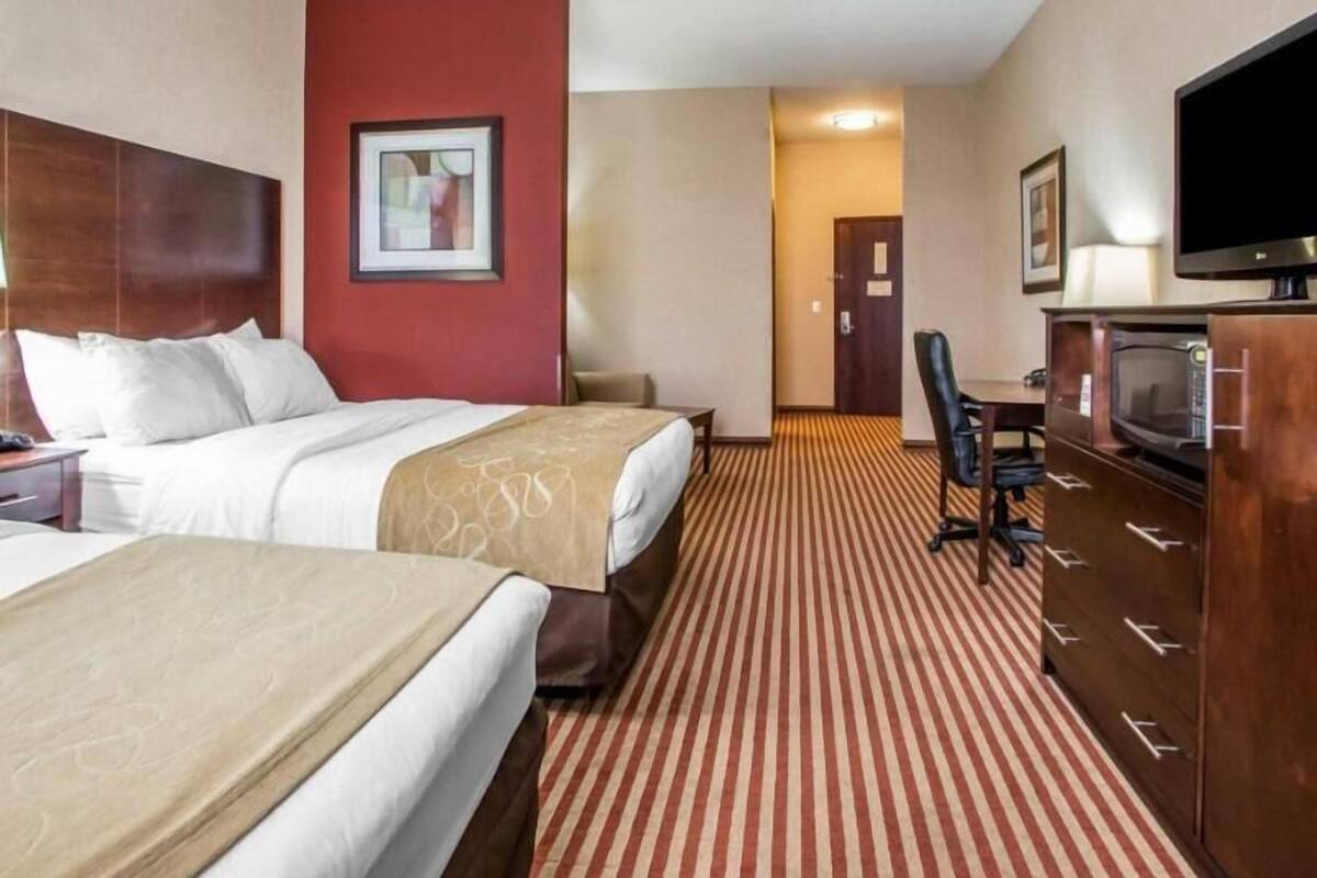 A hotel room with two beds, a TV, a desk, and a microwave.