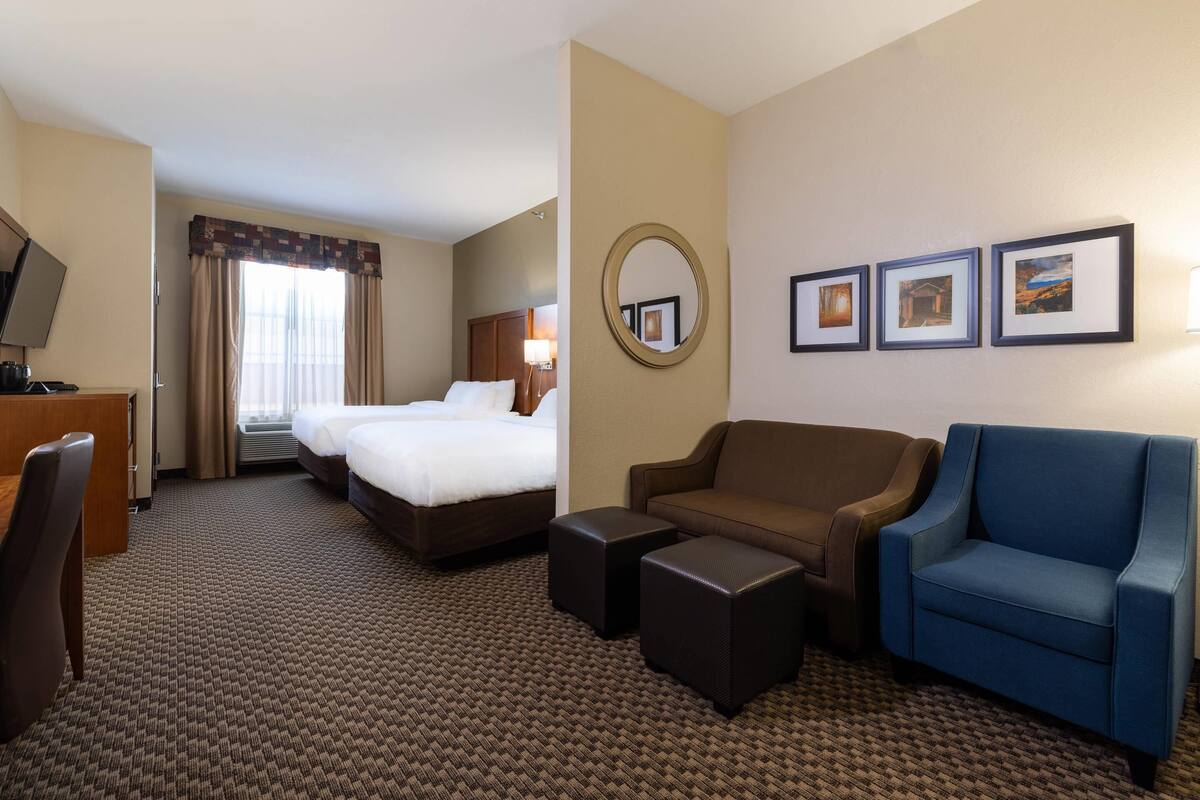A hotel room with a bed, two armchairs, a sofa, a desk, and a TV.