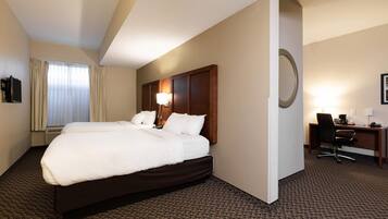 A hotel room with two beds, a desk, a chair, a lamp, and a large mirror.