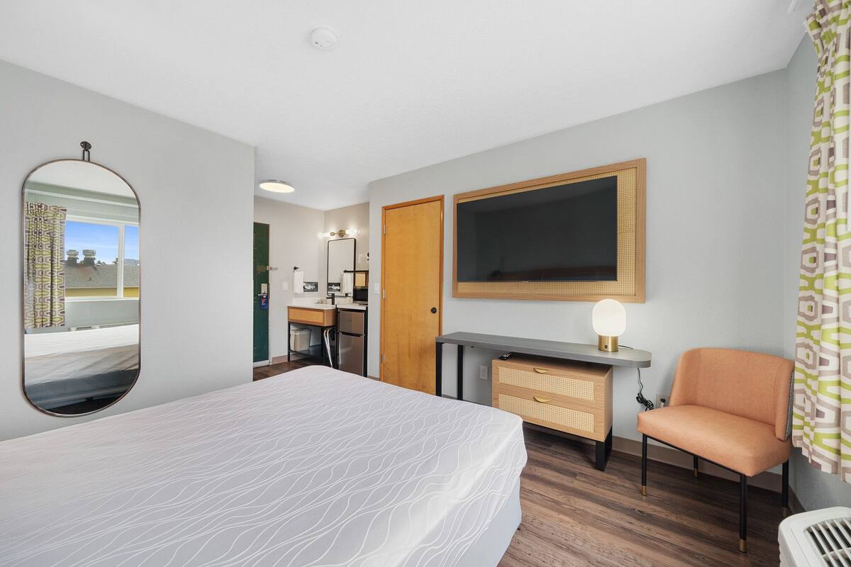 Une chambre d’hôtel comprenant un lit, un bureau avec un ordinateur, une télévision et une chaise.
