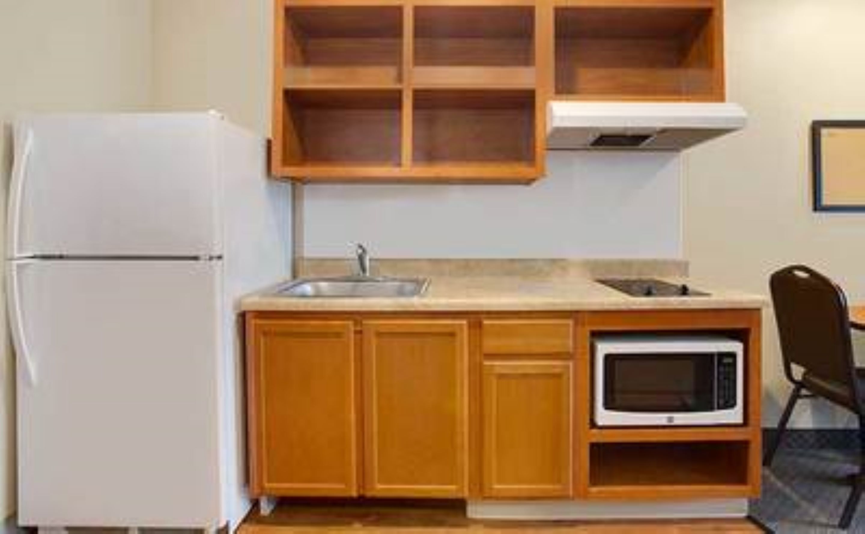 Une cuisine compacte avec des meubles en bois, un four à micro-ondes encastré et un réfrigérateur.