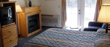 Una habitación de hotel con cama, televisión, chimenea, escritorio y una silla.