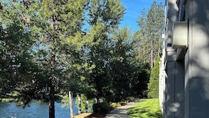 A pathway beside a body of water, lined with trees and a building. - Edgewater Inn Shady Cove (Shady Cove)