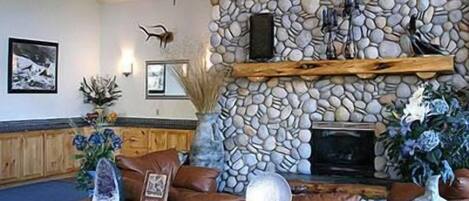 A stone fireplace, leather furniture, and decorative items in a room.